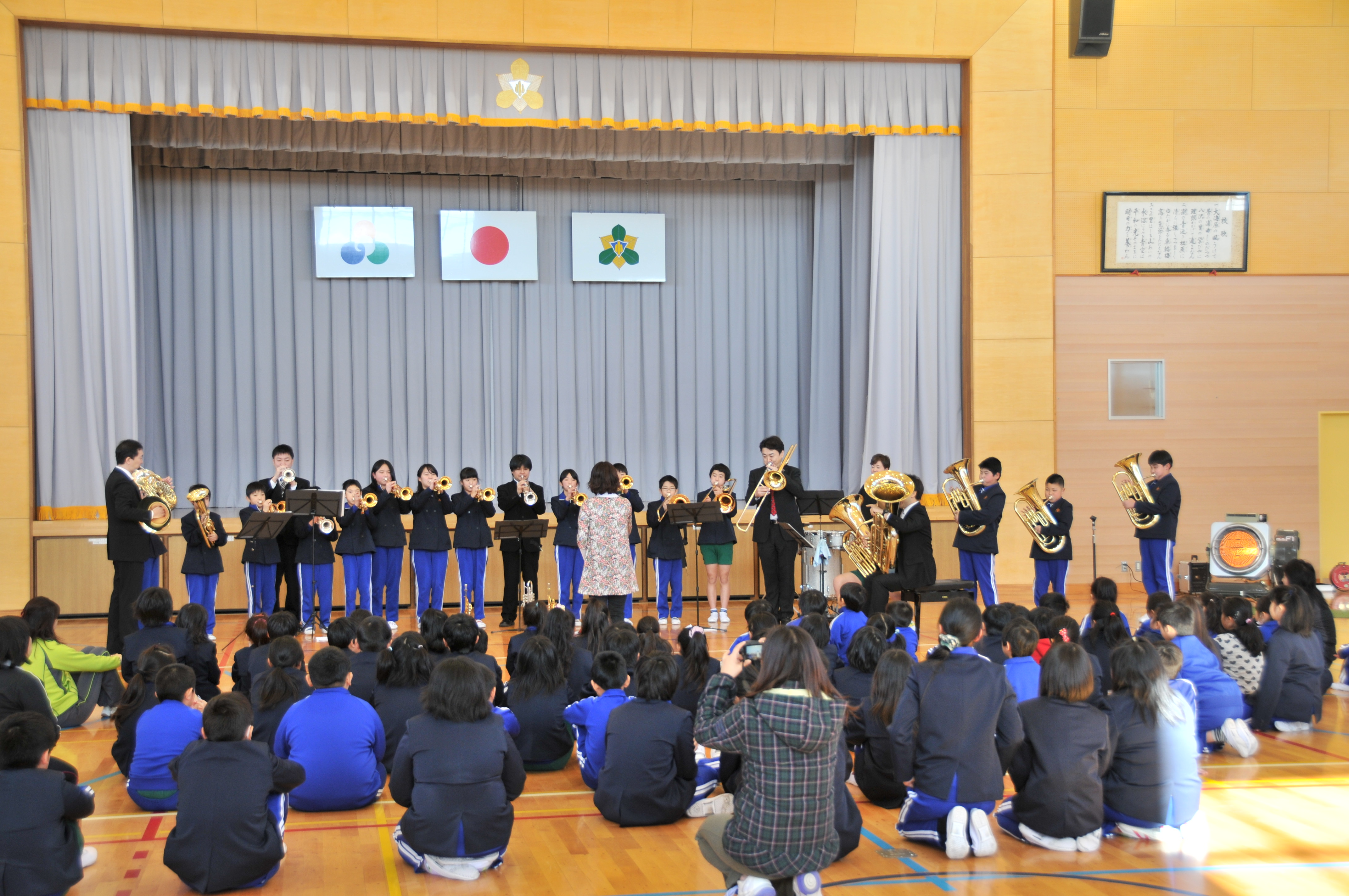 学校の体育館で吹奏楽部の生徒たちと共演している様子